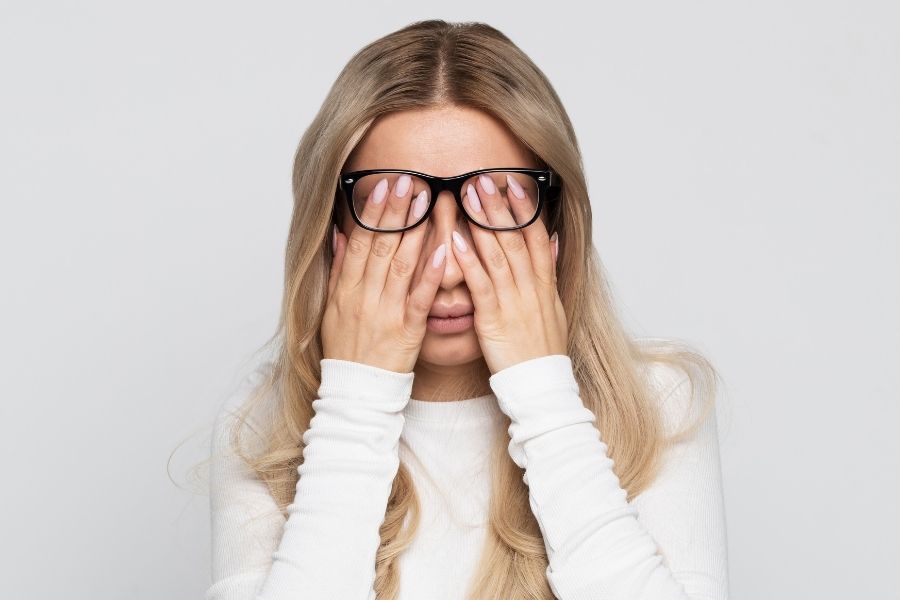 fatigued woman with glasses rubbing her eyes