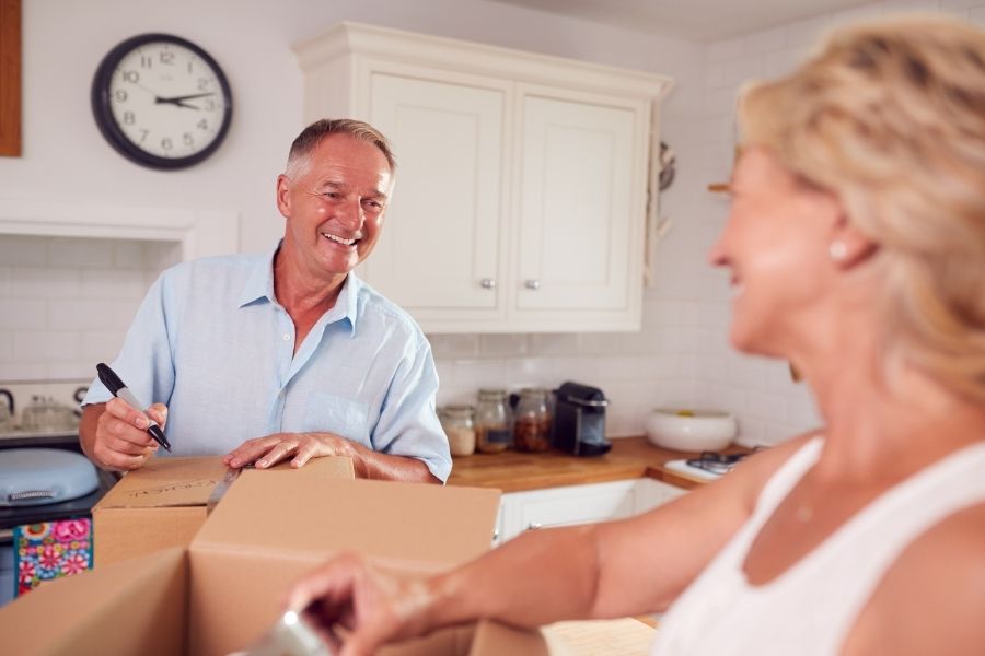Elderly couple packing boxes in their kitchen and downsizing their home