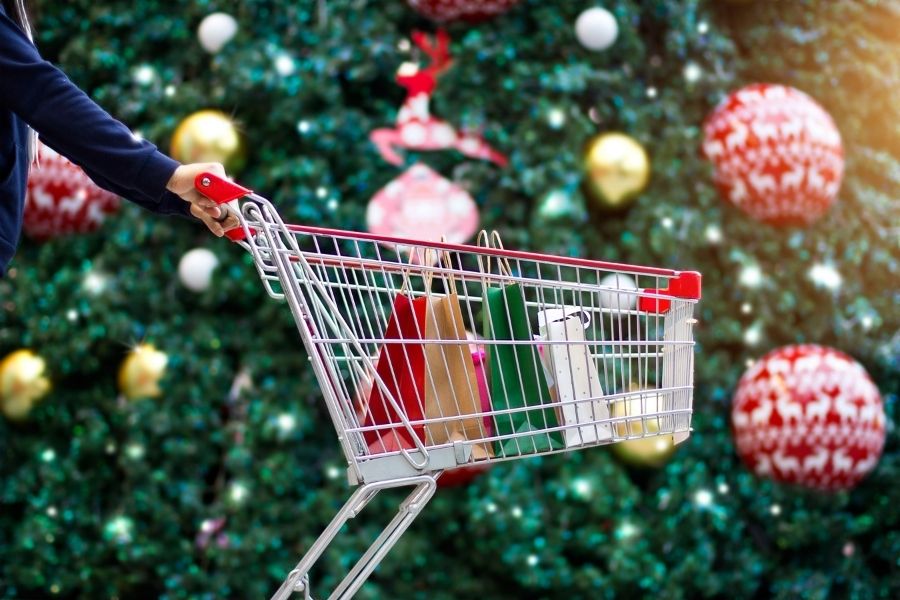 Shopping cart with gifts behind a Christmas tree