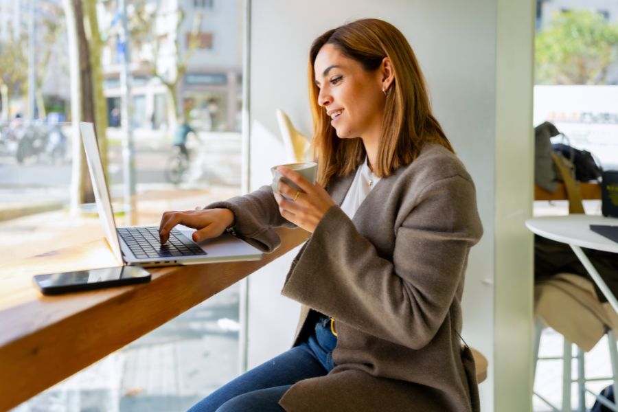 Woman remote working at cafe enjoying coffee